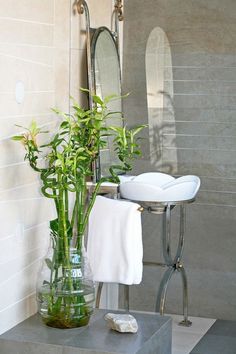 there is a vase with some plants in it next to a mirror and stools