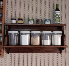 a shelf filled with lots of containers next to a wall mounted spice rack in a kitchen