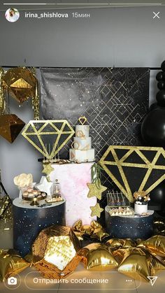 a table topped with lots of gold foil balloons and black and white cake covered in confetti