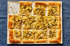 an overhead view of several square pizzas on a white plate with green toppings