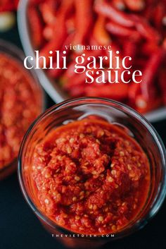 chili garlic sauce in a glass bowl on a table with red peppers and other ingredients