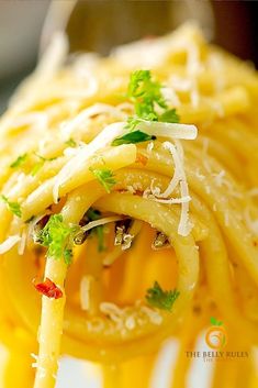 pasta with parmesan cheese and parsley on the top is being held by a fork