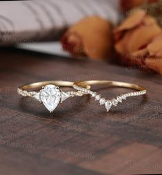 two gold rings with white diamonds on top of a wooden table next to a baby