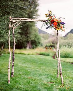 a wooden arch decorated with flowers and greenery for an outdoor wedding in the mountains