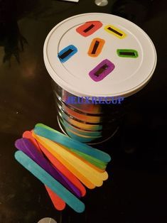 there are many different colored toothbrushes in the cup and on the table next to each other