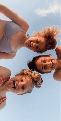 three women in bathing suits are looking up at the camera with their heads tilted to the side