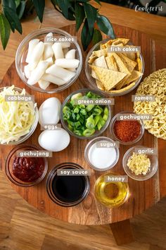 the ingredients for this dish are arranged on a wooden table with green onions, cheese, and sauces