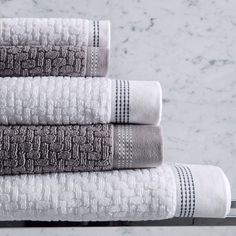 three towels stacked on top of each other in front of a marble wall and floor