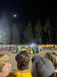 a group of people standing around each other in front of a crowd at night time