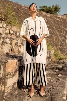 Black, white tunic with lino print and mandarin collared neckline. Paired with striped flared culottes.
Components: 2
Pattern: Printed
Type Of Work: Lino, stripe
Neckline: Mandarin collar
Sleeve Type: Three quarter
Fabric: Mul Cotton
Color: Black,White
Other Details: 
Side seam pockets
Front button detailing
Length:
Tunic: 37.5 inches
Culottes: 35.5 inches
Neck Depth: 10.5 inches
Occasion: Work - Aza Fashions Three Quarter Pants, Crop Top Lehenga, Womens Wrap Dress, Men's Ethnic Wear, Sustainable Clothing Brands, White Tunic, Sustainable Fashion Brands, Top Pants Set, Co Ord Set