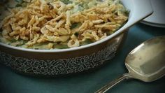 a casserole dish filled with green beans and noodles next to a silver spoon