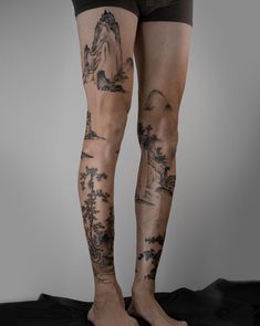 a man's legs with tattoos on them are shown in front of a gray background