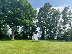 a person standing in the middle of a field with a frisbee golf net