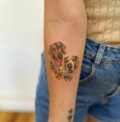 a woman's arm with two dogs on it and flowers around the wrist tattoo