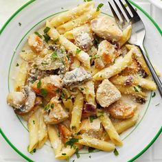 pasta with chicken and parmesan cheese on a white plate next to a fork