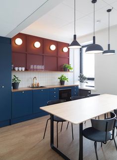 a kitchen with blue cabinets and white counter tops is pictured in this image, there are four hanging lights above the dining table