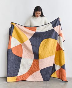 a woman is holding up a quilt that has been made to look like an abstract design