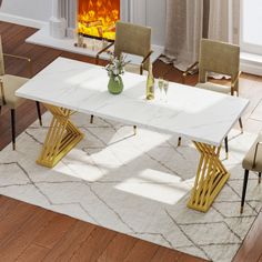 a white table with gold legs in front of a fire place and chairs around it