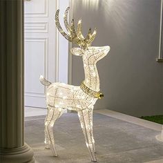 a lighted deer standing in the middle of a room next to a pillar and door