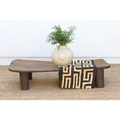 a wooden table with a vase on top of it and a black and white rug