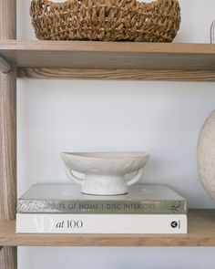 a white bowl sitting on top of a stack of books next to a wicker basket