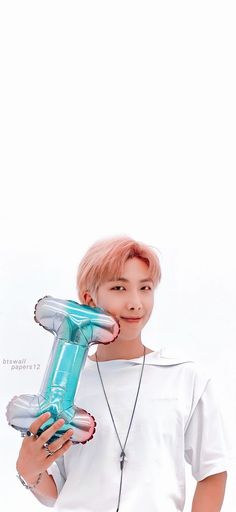 a woman holding a blow dryer up to her face while standing in front of a white background