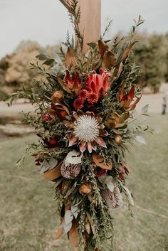 a floral arrangement hanging from a wooden cross