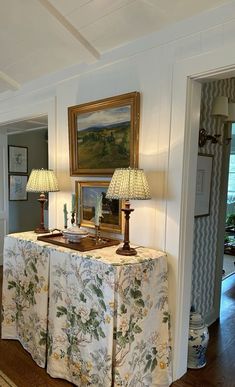 a table with two lamps on it in the middle of a room next to a doorway