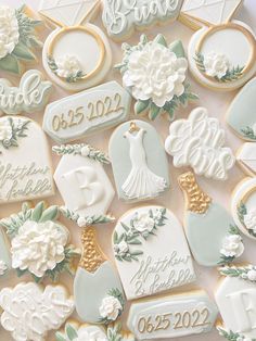 wedding cookies decorated with white flowers and gold trimmings are displayed on a table