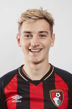 a young man wearing a red and black soccer uniform smiles at the camera while standing in front of a white background