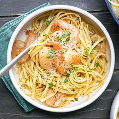 shrimp and pasta with parmesan cheese in a white bowl on a wooden table