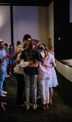 a group of people hugging each other in a room