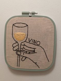 a hand holding a wine glass with the word vino on it