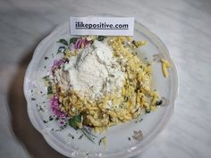 a white plate topped with pasta and other food on top of a marble countertop