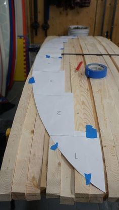 a surfboard sitting on top of a wooden table in a workshop with tape and glue