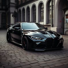 a black sports car parked in front of a building on a cobblestone street