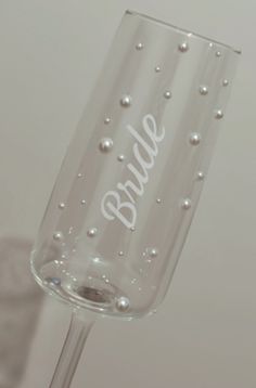 a wine glass with the word bride written on it and pearls in the bottom half