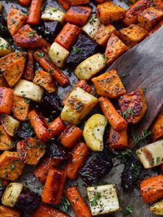 roasted carrots and potatoes with herbs on a baking sheet