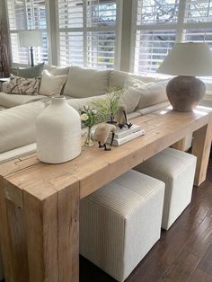 a living room with white couches and wooden table in front of large windowed windows