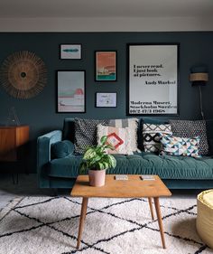 a living room with blue couches and pictures on the wall above it, along with a coffee table