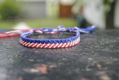 two red, white and blue braided bracelets sitting on top of a table