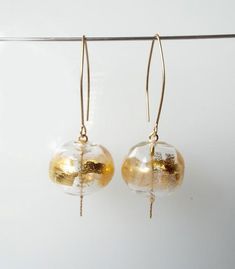 Give some subtle glitz to your look. This Statement Gold Glass Dangle earrings made of clear glass hollow beads decorated with bits of 24 karat gold leaf, Hanging on gold-filled hooks. These Clear blown elegant beaded earrings, add a touch of golden sparkle to your outfit. Whether you pair them with your favorite sundress or jeans and a blouse, you’re going to love these Clear glass earrings!Features:~ Handmade~ Made to order~ Materials: glass, gold-filled hooks, 24 karat gold leaf~ Lampwork bea Elegant Round Glass Earrings, Formal Gold Glass Earrings, Modern Gold Glass Earrings, Gold Glass Earrings For Pierced Ears, Elegant Gold Glass Earrings, Elegant Glass Beaded Drop Earrings, Glass Beaded Dangle Earrings For Parties, Elegant Glass Earrings For Party, Gold Beaded Glass Earrings