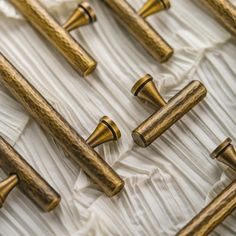 several wooden handles are lined up on a white sheeted tablecloth with gold trimmings