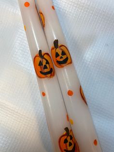 two white candles decorated with pumpkins on them