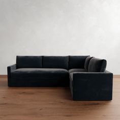 a black couch sitting on top of a hard wood floor next to a white wall