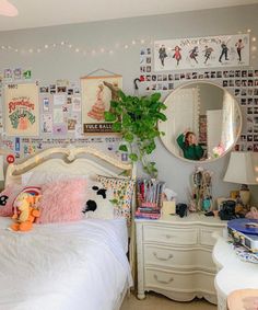 a white bed sitting in a bedroom next to a wall with pictures hanging on it