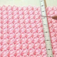 someone is measuring the length of a crocheted blanket with a ruler in front of them