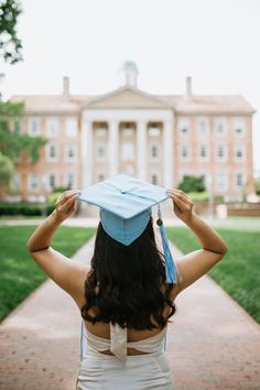 a woman wearing a blue graduation cap and gown standing in front of a large building