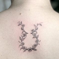 the back of a woman's neck with flowers and leaves on it, as well as an arrow