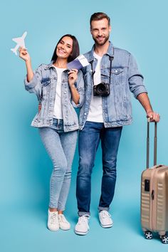 a man and woman are standing next to each other with their suitcases, one holding a paper airplane